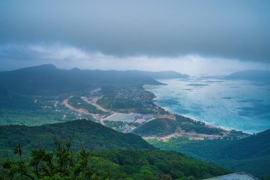 Panoramik kıyı kıyı şeridi Con Dao adası yukarıdan, dalgalar, kıyı şeridi, açık gökyüzü ve yol, mavi deniz ve dağ. Con Dao 'nun yeni yolcu portu.