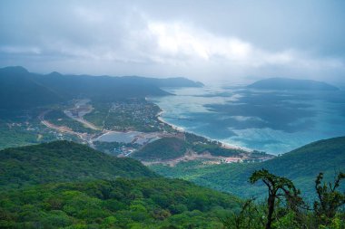 Panoramik kıyı kıyı şeridi Con Dao adası yukarıdan, dalgalar, kıyı şeridi, açık gökyüzü ve yol, mavi deniz ve dağ. Con Dao 'nun yeni yolcu portu.