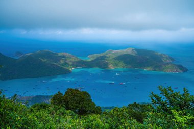 Panoramik kıyı kıyı şeridi Con Dao adası yukarıdan, dalgalar, kıyı şeridi, açık gökyüzü ve yol, mavi deniz ve dağ. Con Dao 'nun yeni yolcu portu.