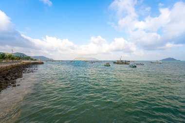 Güneş batarken sakin deniz Con Dao Adası üzerindeki bulutların arasından. Gün batımında gökyüzü ve bulutların arasında güneş olan sakin bir deniz. Meditasyon okyanusu ve gökyüzü arka planı. Huzurlu deniz manzarası.