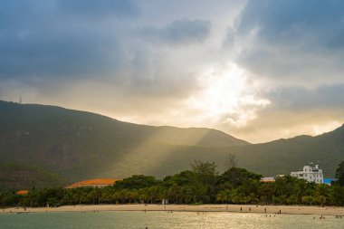 Güneş batarken sakin deniz Con Dao Adası üzerindeki bulutların arasından. Gün batımında gökyüzü ve bulutların arasında güneş olan sakin bir deniz. Meditasyon okyanusu ve gökyüzü arka planı. Huzurlu deniz manzarası.