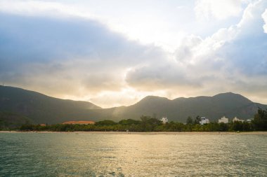 Güneş batarken sakin deniz Con Dao Adası üzerindeki bulutların arasından. Gün batımında gökyüzü ve bulutların arasında güneş olan sakin bir deniz. Meditasyon okyanusu ve gökyüzü arka planı. Huzurlu deniz manzarası.