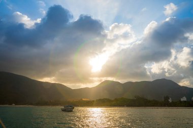 Güneş batarken sakin deniz Con Dao Adası üzerindeki bulutların arasından. Gün batımında gökyüzü ve bulutların arasında güneş olan sakin bir deniz. Meditasyon okyanusu ve gökyüzü arka planı. Huzurlu deniz manzarası.
