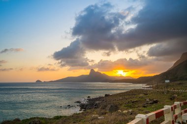 Panoramik Con Dao adası manzaralı, dalgalar, kıyı şeridi, açık gökyüzü ve yol, mavi deniz ve dağ. Bai Nhat Sahili 'nin havadan görünüşü ve sinematik gün batımı..