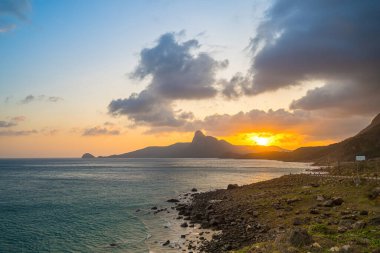 Panoramik Con Dao adası manzaralı, dalgalar, kıyı şeridi, açık gökyüzü ve yol, mavi deniz ve dağ. Bai Nhat Sahili 'nin havadan görünüşü ve sinematik gün batımı..