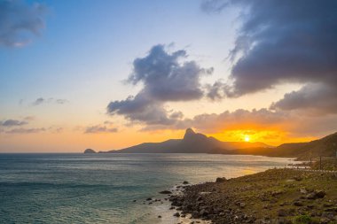 Panoramik Con Dao adası manzaralı, dalgalar, kıyı şeridi, açık gökyüzü ve yol, mavi deniz ve dağ. Bai Nhat Sahili 'nin havadan görünüşü ve sinematik gün batımı..