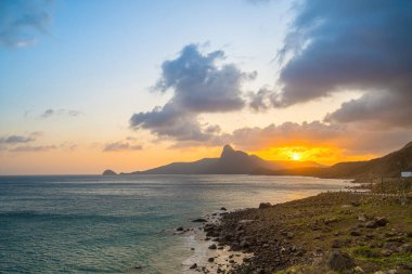 Panoramik Con Dao adası manzaralı, dalgalar, kıyı şeridi, açık gökyüzü ve yol, mavi deniz ve dağ. Bai Nhat Sahili 'nin havadan görünüşü ve sinematik gün batımı..