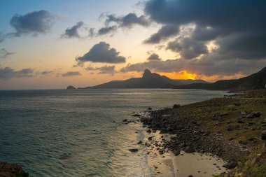 Panoramik Con Dao adası manzaralı, dalgalar, kıyı şeridi, açık gökyüzü ve yol, mavi deniz ve dağ. Bai Nhat Sahili 'nin havadan görünüşü ve sinematik gün batımı..