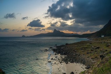 Panoramik Con Dao adası manzaralı, dalgalar, kıyı şeridi, açık gökyüzü ve yol, mavi deniz ve dağ. Bai Nhat Sahili 'nin havadan görünüşü ve sinematik gün batımı..