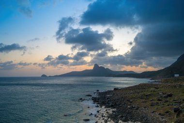 Panoramik Con Dao adası manzaralı, dalgalar, kıyı şeridi, açık gökyüzü ve yol, mavi deniz ve dağ. Bai Nhat Sahili 'nin havadan görünüşü ve sinematik gün batımı..