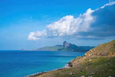 Panoramik Con Dao adası manzaralı, dalgalar, kıyı şeridi, açık gökyüzü ve yol, mavi deniz ve dağ. Bulutlu bir günde Bai Nhat plajının havadan görüntüsü. Seyahat kavramı