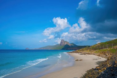 Panoramik Con Dao adası manzaralı, dalgalar, kıyı şeridi, açık gökyüzü ve yol, mavi deniz ve dağ. Bulutlu bir günde Bai Nhat plajının havadan görüntüsü. Seyahat kavramı