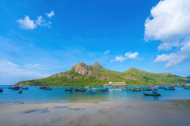 Panoramik Con Dao adası manzaralı, dalgalar, kıyı şeridi, açık gökyüzü ve yol, mavi deniz ve dağ. Bulutlu bir günde Bai Nhat plajının havadan görüntüsü. Seyahat kavramı