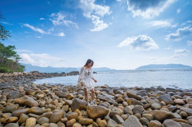 Yaz tatili. Gülümseyen Asyalı kadınlar, dinleniyor ve ayakta, sahilde yürüyorlar Con Dao, tatilde çok mutlu ve lüks, açık havada gökyüzü arka planında. Seyahat ve yaşam tarzı kavramı.