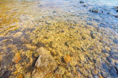 Deniz dalgalarının hava manzarası ve muhteşem Rocky sahili, güzel, berrak sualtı yüzeyi. Şeffaf mavi suyun altında denizin dibi kayalık. Berrak turkuaz deniz yüzeyi güneş ışınları yansımasıyla dalgalanır..
