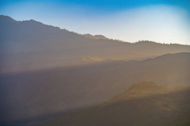 Turuncu gökyüzünde gümüş astar ve bulut ile güçlü gündoğumunun muhteşem manzarası. Dağların panoramik manzarası, gündoğumunda sisli tepelerle sonbahar manzarası