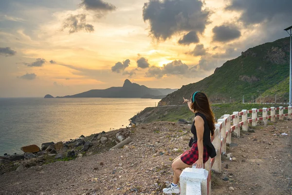 海岸線 澄んだ空と道路 白Nhacビーチで映画の夕日と青い海と山で 上記からの海岸コンダオ島の景色の前に座っている若い女の子の観光客のバックビュー — ストック写真