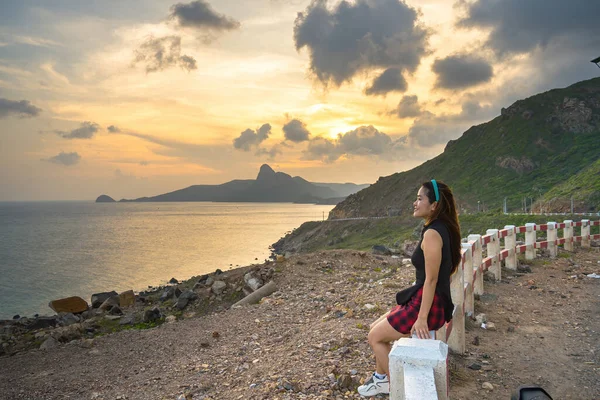 海岸線 澄んだ空と道路 白Nhacビーチで映画の夕日と青い海と山で 上記からの海岸コンダオ島の景色の前に座っている若い女の子の観光客のバックビュー — ストック写真