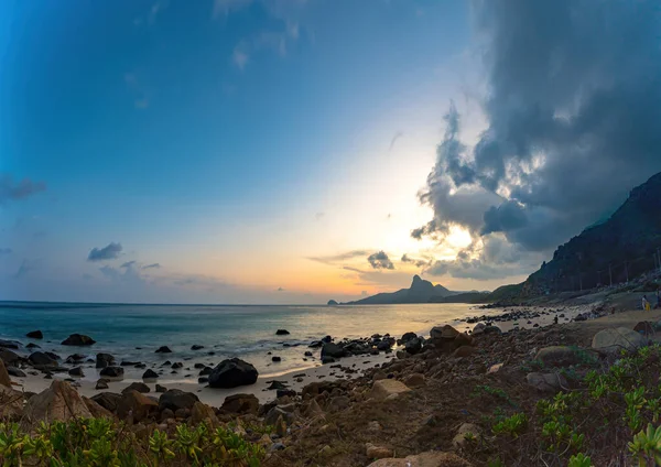 Panoramik Con Dao adası manzaralı, dalgalar, kıyı şeridi, açık gökyüzü ve yol, mavi deniz ve dağ. Bai Nhat Sahili 'nin havadan görünüşü ve sinematik gün batımı..