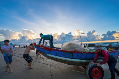 Vung Tau, VIETNAM - 14 Mayıs 2023: Balıkçı ağlarını gün doğumunda ya da günbatımında atıyor. Geleneksel balıkçılar balık ağını hazırlıyor.