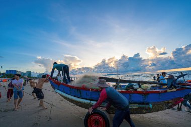 Vung Tau, VIETNAM - 14 Mayıs 2023: Balıkçı ağlarını gün doğumunda ya da günbatımında atıyor. Geleneksel balıkçılar balık ağını hazırlıyor.