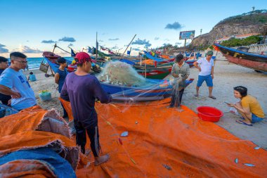 Vung Tau, VIETNAM - 14 Mayıs 2023: Balıkçı ağlarını gün doğumunda ya da günbatımında atıyor. Geleneksel balıkçılar balık ağını hazırlıyor.