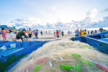 Vung Tau, VIETNAM - 14 Mayıs 2023: Balıkçı ağlarını gün doğumunda ya da günbatımında atıyor. Geleneksel balıkçılar balık ağını hazırlıyor.