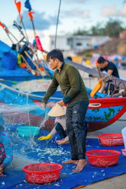 Vung Tau, VIETNAM - 14 Mayıs 2023: Balıkçı ağlarını gün doğumunda ya da günbatımında atıyor. Geleneksel balıkçılar balık ağını hazırlıyor.