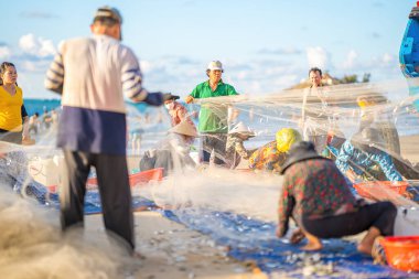 Vung Tau, VIETNAM - 14 Mayıs 2023: Balıkçı ağlarını gün doğumunda ya da günbatımında atıyor. Geleneksel balıkçılar balık ağını hazırlıyor.