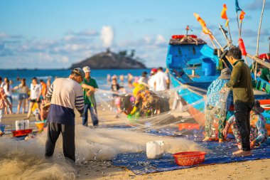 Vung Tau, VIETNAM - 14 Mayıs 2023: Balıkçı ağlarını gün doğumunda ya da günbatımında atıyor. Geleneksel balıkçılar balık ağını hazırlıyor.