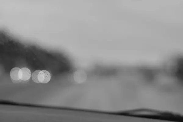 Yağmurda tek renkli bulanık bir araba ışığı.