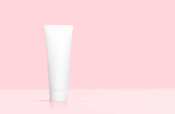 White plastic tube cream mockup on a pale pink background.