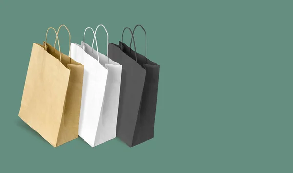 Blank paper bags with handles for shopping on green background
