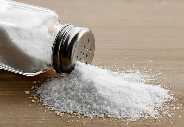 Salt Glas Shaker Och Hög Med Spillt Salt Ett Träbord — Stockfoto