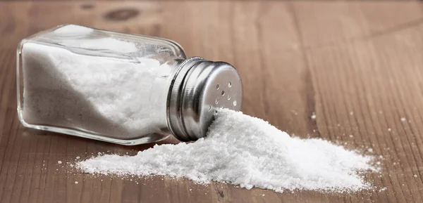 Salt Glas Shaker Och Hög Med Spillt Salt Ett Träbord — Stockfoto