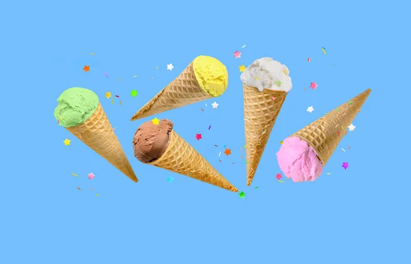 ワッフルコーンのアイスクリームのスクープは 青い背景の上を飛ぶスパイクと バースデーまたは休日の背景 — ストック写真