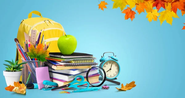 Yellow backpack, alarm clock and school equipment. Back to school concept with copy space
