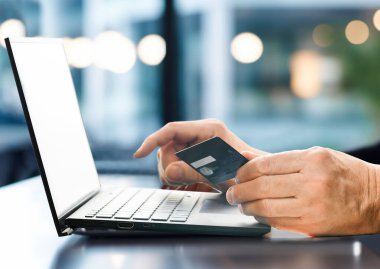 İnternetten alışveriş. Kredi kartı tutan ve dizüstü bilgisayar kullanan bir adam. Kafede, ofiste çalışan bir iş adamı. İnternet bankacılığı, çevrimiçi mağaza, ödeme, harcama.