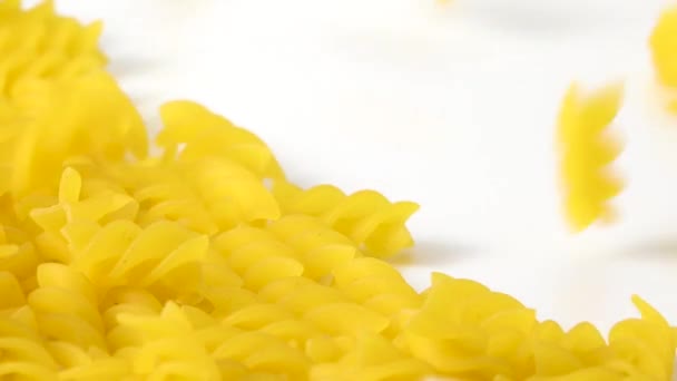 Rauwe Italiaanse Pasta Fusilli Ongekookte Gele Noedels Verspreid Witte Achtergrond — Stockvideo