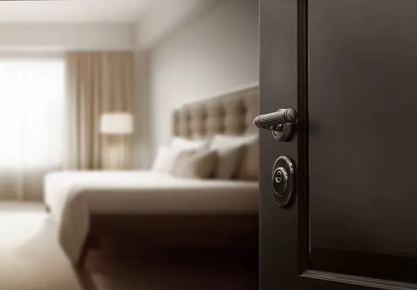 Slightly open door to the hotel room with blurred luxury bedroom