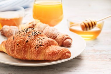 Güne başlamak için taze kruvasan, bal ve meyve suyuyla keyifli bir kahvaltı yapın.