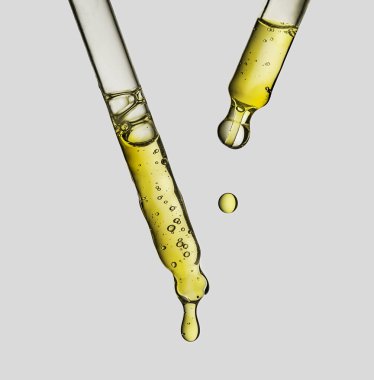 Beyaz arka planda damlatıcıdan damlayan temel serum yağı