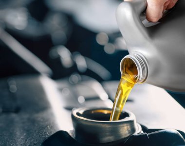 Gümüş plastik kutudan motor yağı dökülüyor. Normal ve rutin araç bakımı motor yağını kullanmak optimum performans seviyelerine ulaşmak için gereklidir