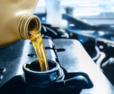 Araba tamir merkezindeki plastik teneke kutudan motor yağı dökülüyor. Normal ve rutin araç bakımı motor yağını kullanmak optimum performans seviyelerine ulaşmak için gereklidir
