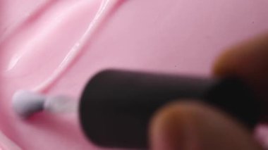 Yakın plan, güzel bir desen ve zengin bir rengi gösteren, fırçayla boyanmış yumuşak pembe tırnak cilasını gösteriyor.