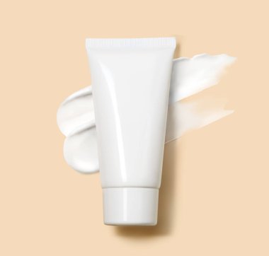 Beyaz kozmetik tüpü, bej arkaplandaki bir smear kozmetik kremin sanatsal arka planına yerleştirilip güzellik markası yaratmak için idealdir..