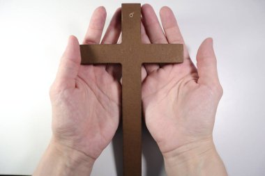 Beyaz arka planda ahşap bir haç tutan eller