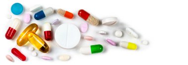 Yukarıdan görülen tablet ve kapsüllerin panoramik yakın plan beyaz arka plan.