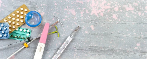 Different contraceptive methods seen from above on a pink and grey background panoramic