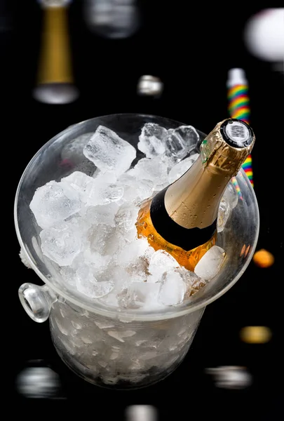 Bottle of Champagne in an ice bucket on a festive background and straw huts